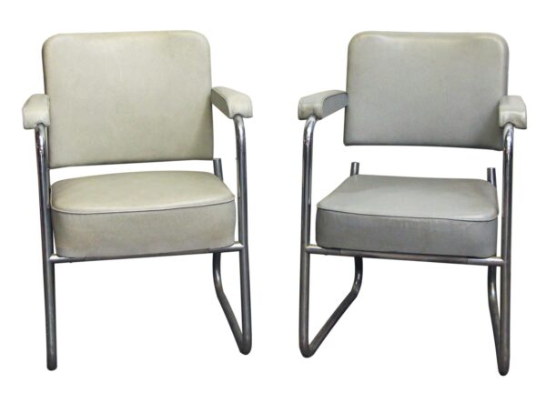 Pair of gray vinyl office arm chairs with chrome-finished steel frames, shown front-facing side by side.