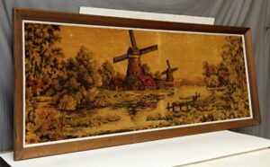 Wood-framed fabric wall art showing a Holland windmill scene in brown and orange tones.
