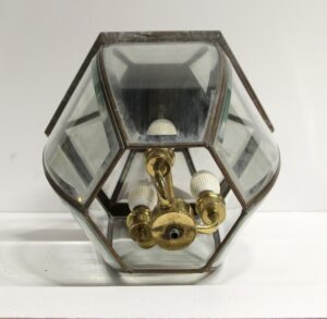 Traditional exterior lantern wall sconce with beveled glass and antique brass trim, shown in a close-up of the three-light interior.