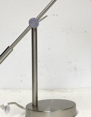 Brushed nickel desk lamp shown in close-up, with an adjustable metal arm and round base.