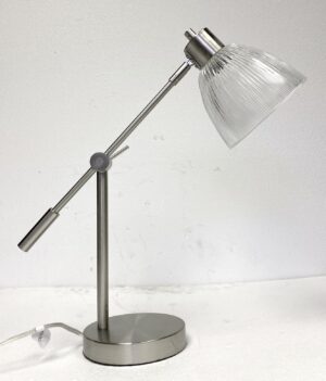 Brushed nickel desk lamp with an adjustable arm and clear prism glass shade, shown from the side with the switch and round base visible.