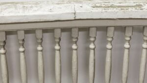 Pair of white wooden bannisters with curved top rails and worn paint, shown in close-up as a matching pair.
