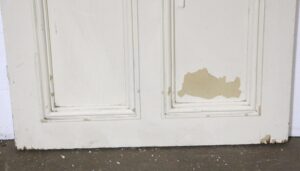 Distressed white six-panel door with curved molding and chipped paint on the lower panels.