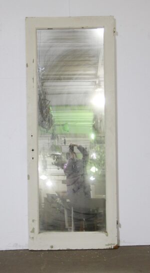 Vintage white closet door with a large mirrored panel, shown upright with worn paint and visible edge hardware on the side.