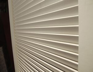 White wooden closet door with horizontal louvers, shown in close-up.