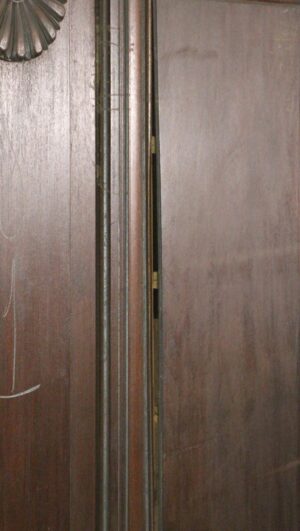 Close-up of a dark wood tone cedar wainscot panel with vertical trim and a partially visible carved rosette at the top left.