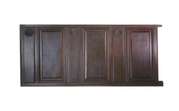 Dark wood wainscot paneling with carved rosette details and raised rectangular panels.