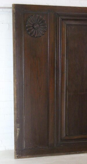 Hand-carved dark wood wainscot paneling with a carved rosette near the top and a raised frame detail.