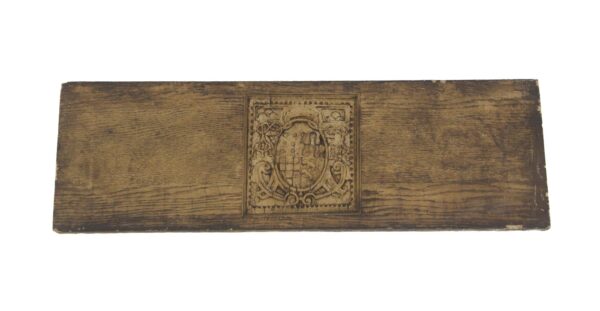 Brown Arts & Crafts pediment with a central coat of arms motif and aged wear.