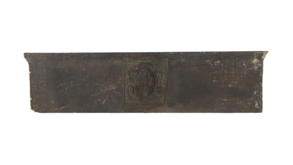 Brown Arts and Crafts pediment with a central coat of arms motif and worn edges.