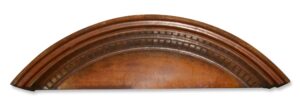 Arched wooden pediment with dentil molding and a curved top profile.