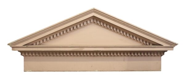 Vintage pink wooden pediment with dentil and crown molding forming a peaked top.