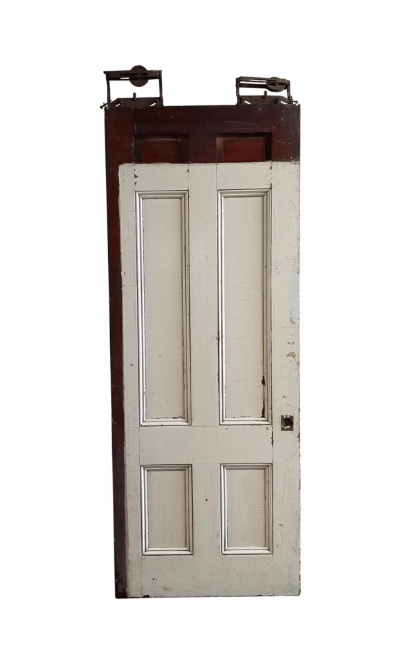 Antique wood pocket door with six panels, white painted lower section, dark stained top and side, and original hardware visible at the top.