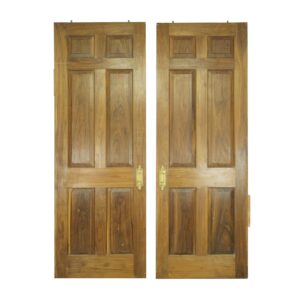 Pair of six-panel wood pocket double doors in a dark wood tone, shown front on with ornate brass pulls and visible age wear.