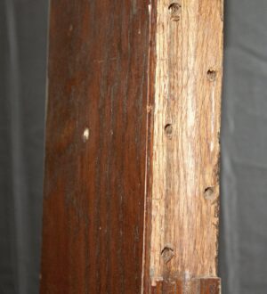 Close-up of a pocket door showing the dark wood tone pine edge with screw holes and the junction where the glass panel would fit.