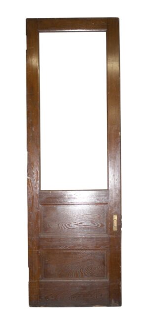 Vintage pine pocket door with a tall top glass opening, two lower panels, and a brass lock plate on the right edge.