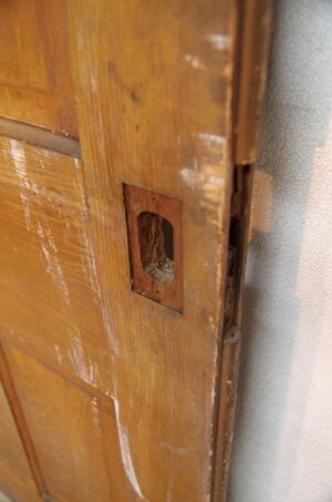 Close-up of a wood pocket door showing the latch mortise and the edge of one panel.