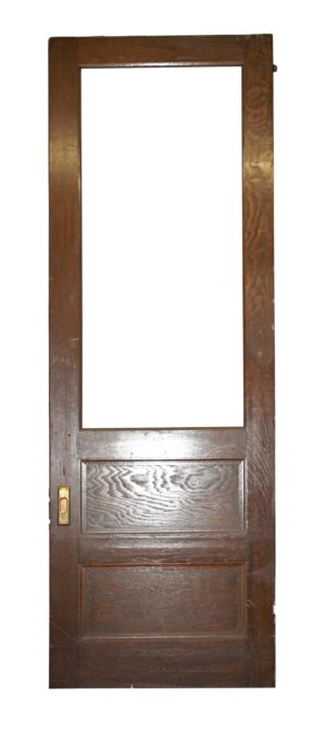 Tall dark wood-tone pocket door with a large upper glass opening, two lower panels, and a brass lock plate on the left side.