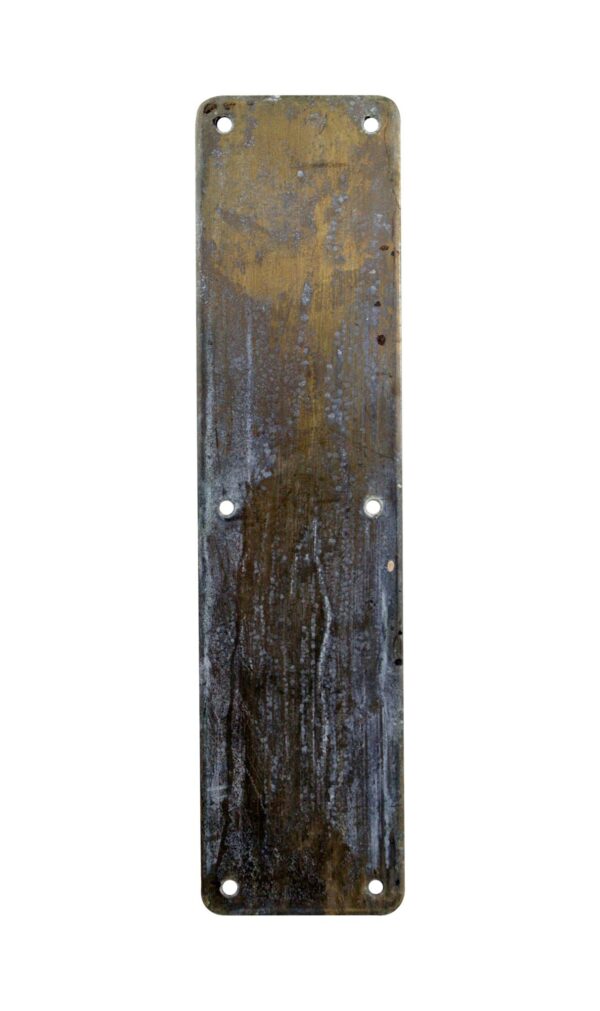 Antique brass door push plate with rounded corners and six mounting holes, shown with some white paint residue on the surface.