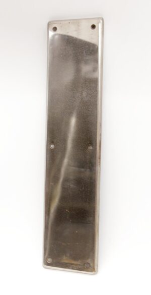 Vertical brushed steel door push plate with four visible mounting holes and a slightly worn, aged surface.