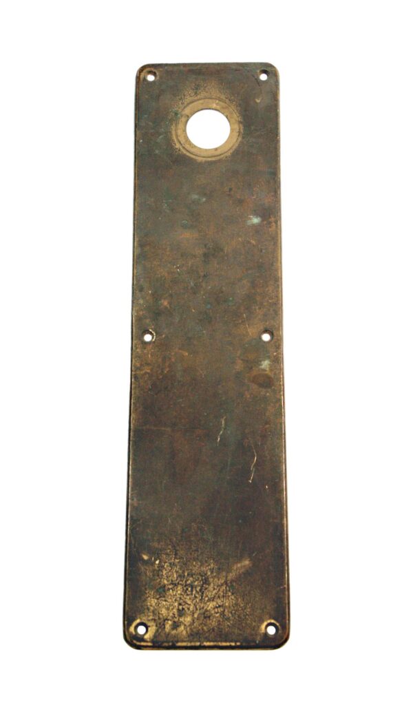 Antique brass door push plate with a round lock insert and four screw holes, shown upright.