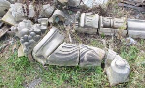 Broken terra cotta cornucopia fragments in gray, showing carved decorative sections and rounded ends.