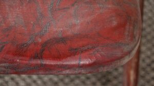 Close-up of a red vinyl chair cushion with black creased patterning and visible tufting.