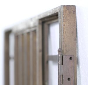 Close-up of an antique bronze Art Deco door edge with a hinge and worn finish.
