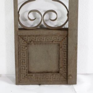 Wrought iron elevator trim piece with scrollwork top and a framed lower panel.