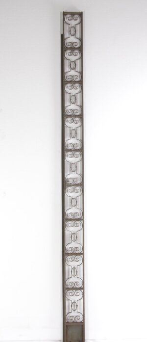 Tall wrought iron elevator trim piece with a narrow rectangular frame and repeating scrollwork panels.
