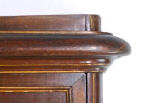 Close-up of the dark wood mirror frame with carved Rococo detailing and trim at the corner.