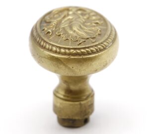 Antique bronze oval door knob with a raised goddess design and a threaded base, shown in close-up from above.
