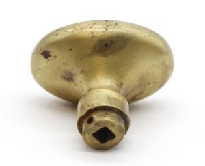 Antique bronze oval door knob with a threaded base and worn surface, shown in close-up from the underside.