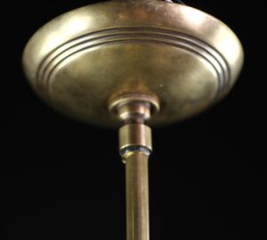 Close-up of a brass pendant light canopy and pole, showing the underside of the fixture.