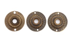 Three antique brass door rosettes with a radial pattern and two screw holes each are shown side by side.