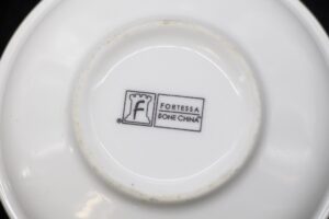 Bottom view of a white bone china soup bowl with the Fortessa mark printed in the center.