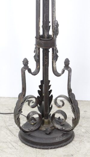 Close-up of a wrought iron floor candelabra base with scrollwork and foliate details in black finish.