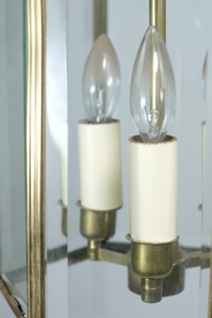 Close-up of a traditional brass lantern light showing two candle-style bulbs with clear glass panels and antique brass detailing.