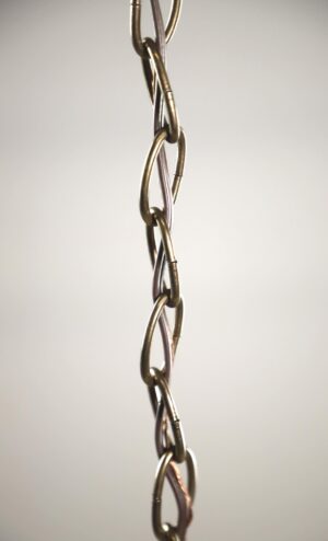 Close-up of an antique brass chain pendant light with linked metal chain details and a milk glass shade partially visible.