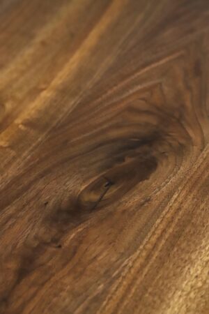 Close-up of a live edge walnut tabletop with visible wood grain and a natural knot detail.