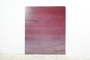 Red glass sheet with a rectangular shape, showing a small chip missing from one corner and worn edges.