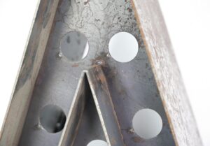 Close-up of a black steel star-shaped light frame with circular cutouts and visible rust, shown without bulbs.