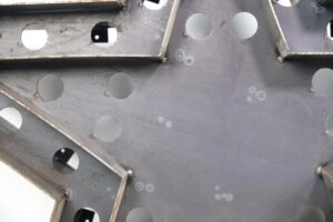Close-up of a black metal star-shaped light frame with circular cutouts and visible rust along the edges, shown without bulbs.