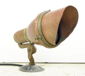 Mountable theater spotlight with a copper and brass housing and a visible blue lens, shown in a side angle on its base.