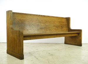 Vintage oak courtroom bench with a high back and simple arms, shown in a side view with visible surface wear and a dark wood tone.