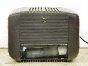 Antique brown plastic radio shown from the back, with a toggle switch centered on the ribbed rear panel and a visible bottom light compartment opening beneath it.