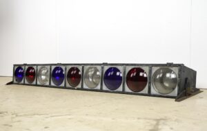 Steel frame stage light with nine round red, white, and blue lenses shown in a wide side view.
