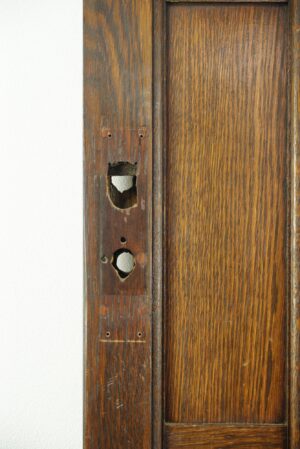 Close-up of an Arts and Crafts wood door showing the lock mortise area and worn dark wood grain.