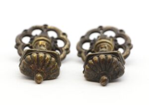 Pair of Victorian brass drawer pulls shown as a matching pair with ornate backplates and drop handles, viewed from the front in close-up.