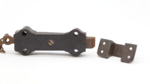 Victorian cast iron surface door bolt with chain, shown with the separate mounting plate and holes visible.